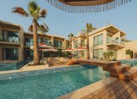 The pool and wooden deck at INZA Ovacık, in front of terraced rooms, palm trees and fringed umbrellas